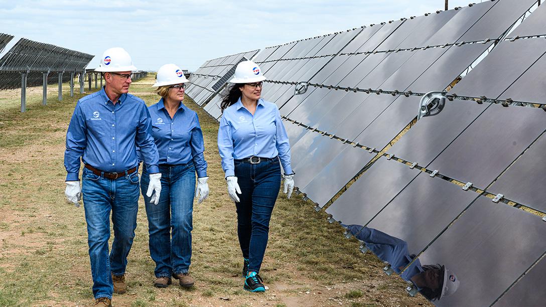 Three employees walking along solar panels at GoldSmith facility